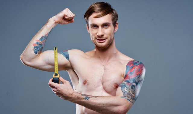 Man with tape measuring his biceps